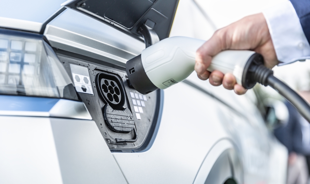 Persona conectando cargador a vehículo eléctrico mostrando alternativa a la gasolina