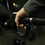 Close-up of a person refueling a car at a gas pump during night.