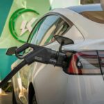 Close-up of Tesla Model 3 connected to a charging station, highlighting eco-friendly transportation.